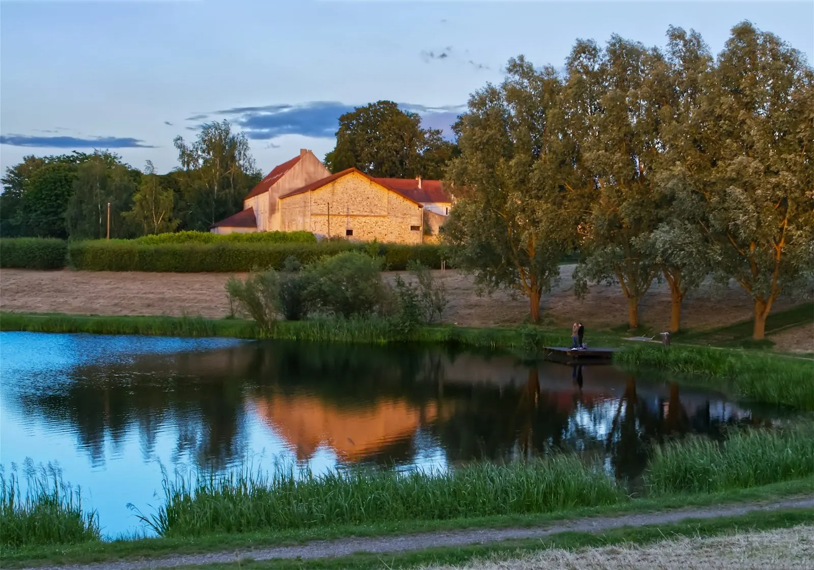 Maison en pierre au bord de l'eau, au soleil couchant (photo d'illustration)